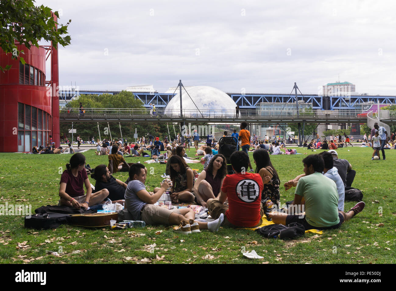Paris Park - Menschen entspannend auf Gras der Park La Villette mit Blick auf Spiegel- dome La Géode, Paris, Frankreich, Stockfoto