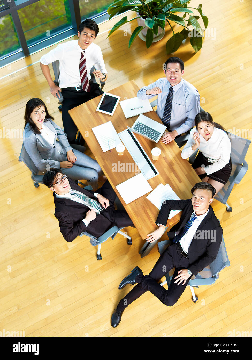 Hohe Betrachtungswinkel und ein Team von asiatischen Führungskräfte an der Kamera schaut lächelnd. Stockfoto