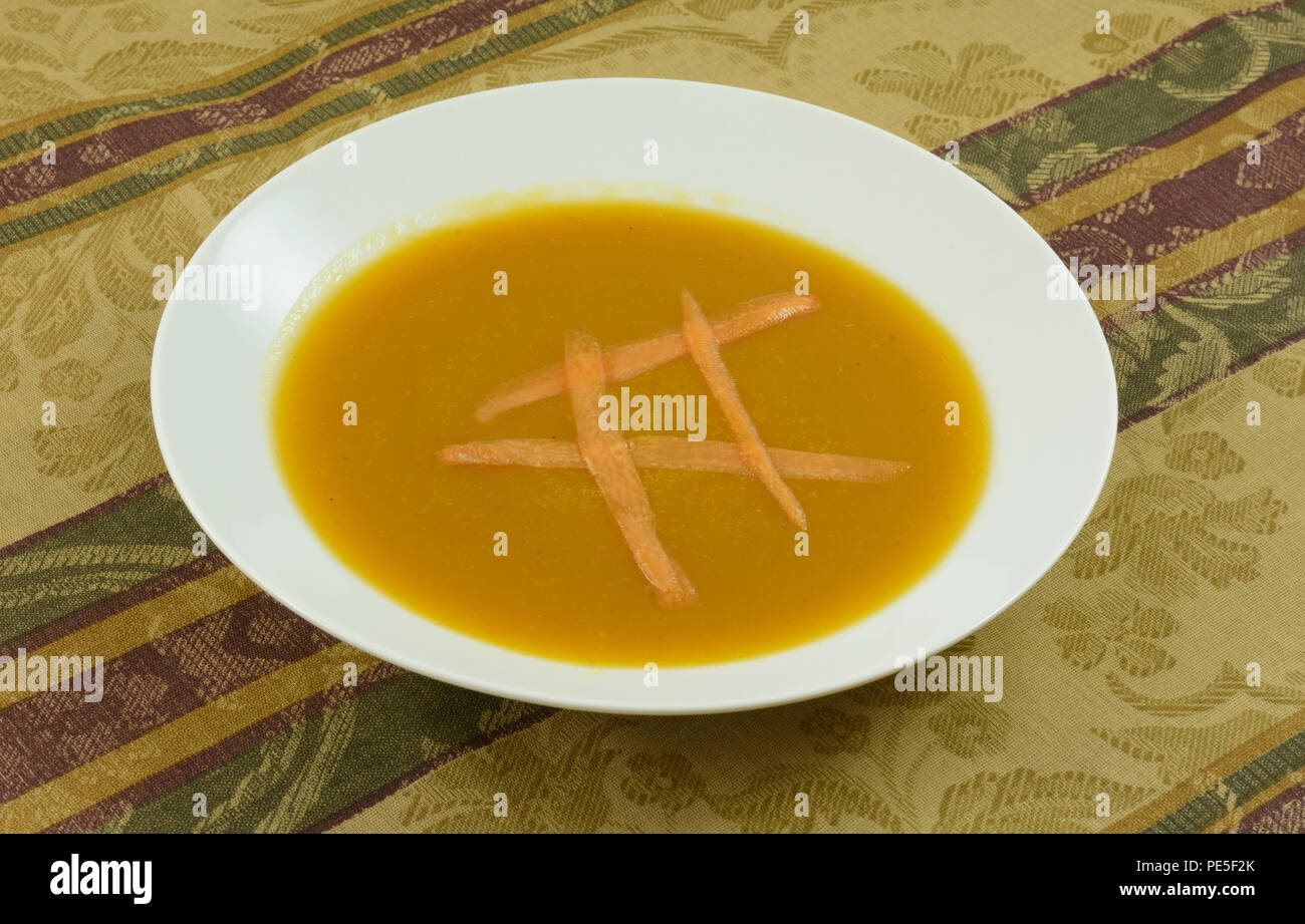 Warme butternut Kürbis Suppe mit Karotte in Weiß Suppenteller auf Tischdecke Stockfoto