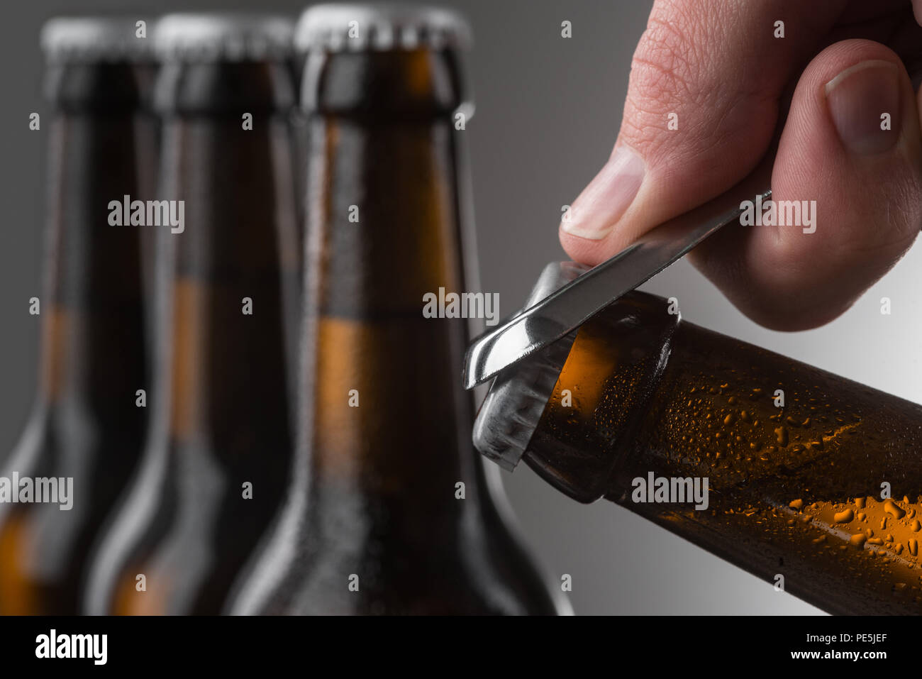 Männliche Hand öffnen Bier Flasche mit Metall Flaschenöffner. Tröpfchen in  braunen Flaschen kaltes Bier. Selektive konzentrieren Stockfotografie -  Alamy