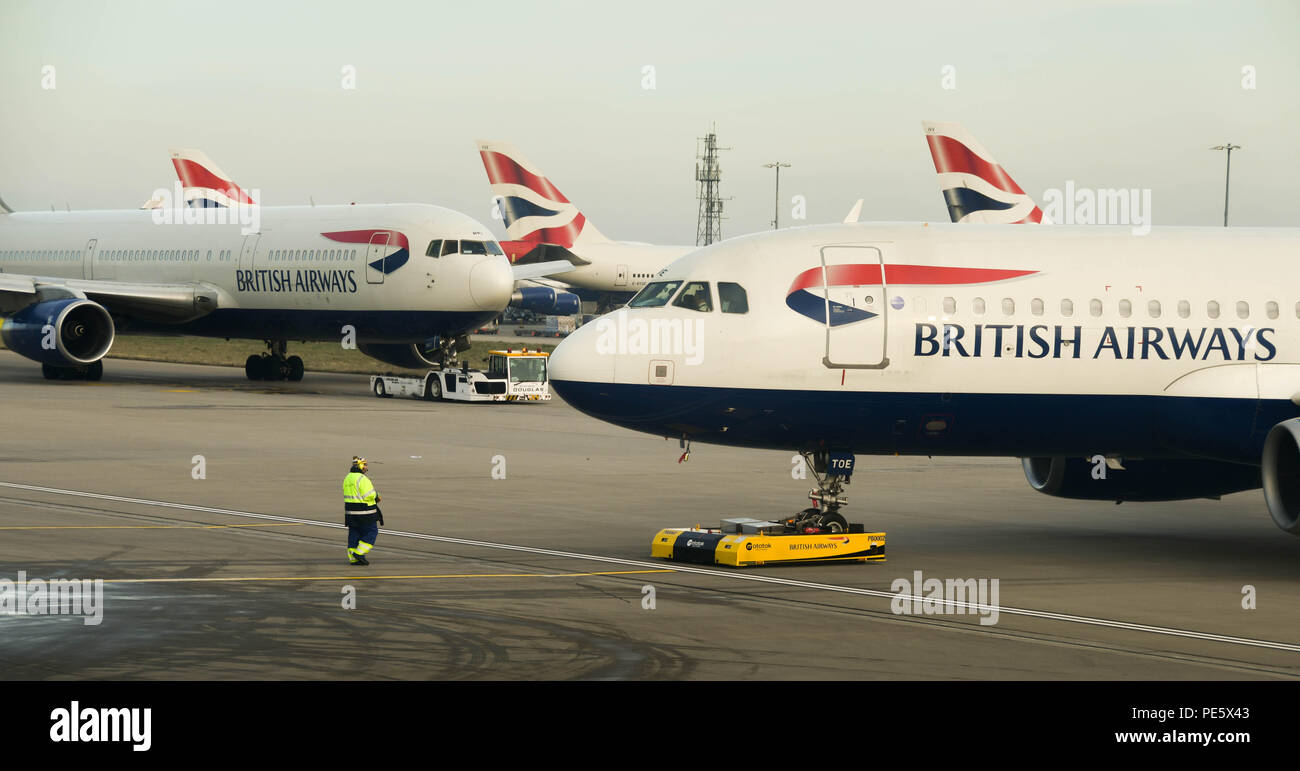 Flughafen Arbeiter den Betrieb eines ferngesteuerten Tauziehen am Flughafen London Heathrow zurück zu schieben, in der der scheidende British Airways Airbus A320 Stockfoto