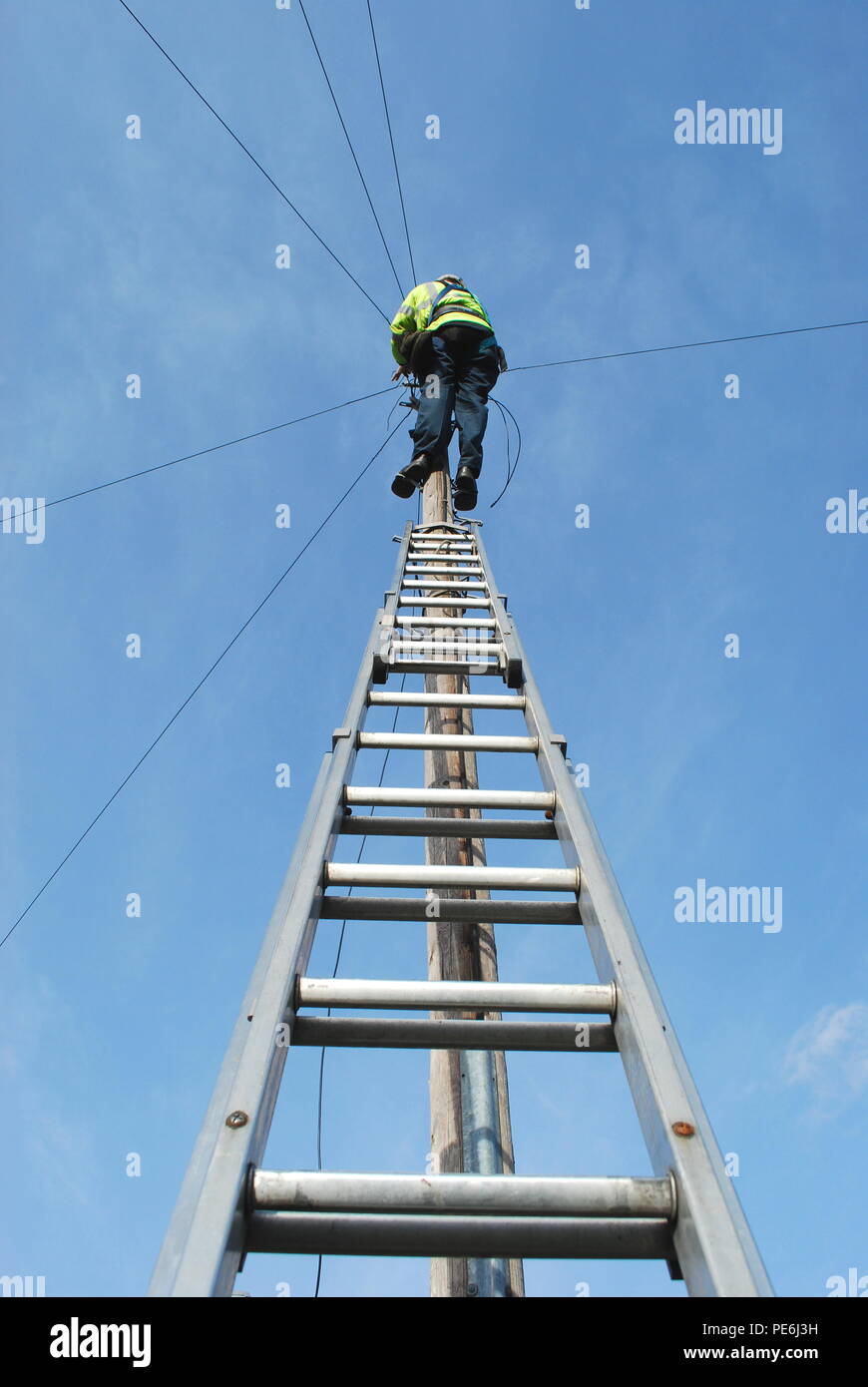 Techniker auf der Leiter Instandsetzung Telefon Kabel gegen den blauen Himmel Stockfoto