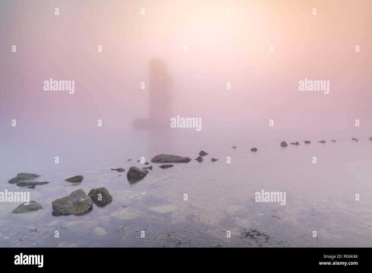 Einer der verbleibenden Säulen der Sturmflutwehr stehend im Wasser während eines schweren dichten Nebel im Winter Sonnenuntergang an der Deltawerke Sturmflut Meer Stockfoto