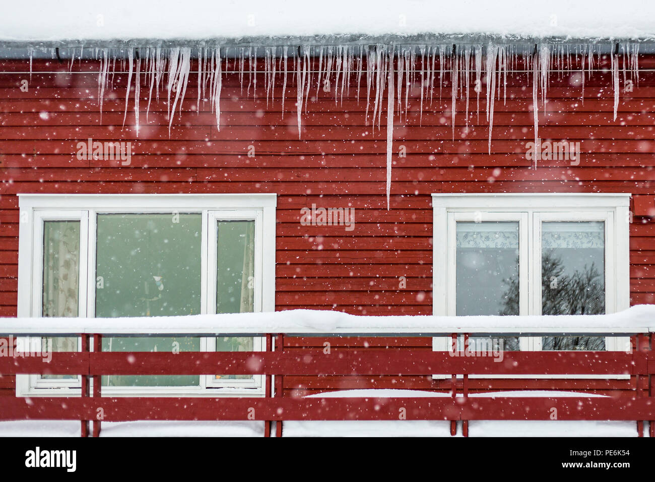 Typische traditionelle Arctic Red House mit Schnee und Eiszapfen in den Bergen auf einem Fjord. Stockfoto