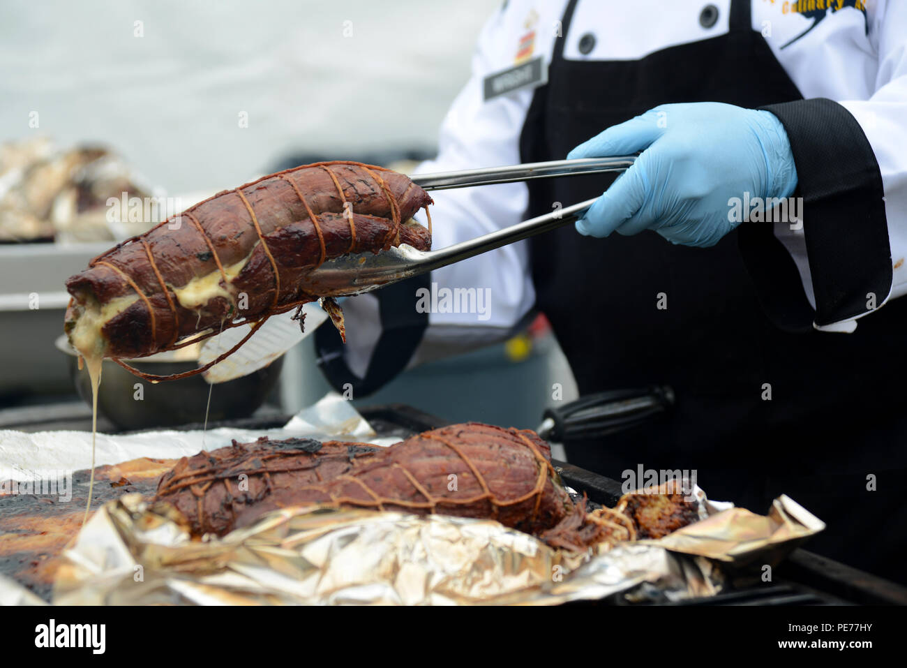 Gemeinsame Basis Elmendorf-Richardson Küchenteam kochen Pfc. Allan Wright entfernt den Spinat und provolone Flank Steak vom Grill in der Alaska State Fair Rindfleisch Showdown 2015, Sept. 6 gefüllt. Dieses letzte Gericht aus Spinat und Provolone gefüllte Flank Steak, Käse-Kraut Kroketten, gepfeffert Schinken eingewickelten Spargel, Feuer - gebratene Tomaten und Karotten pürieren. Der Wettbewerb umfasst drei Teams, die jeweils mit drei Hauptgerichten für die Richter und etwa 300 Probenehmer für die Masse. (U.S. Air Force Foto/Airman 1st Class Christopher R. Morales) Stockfoto