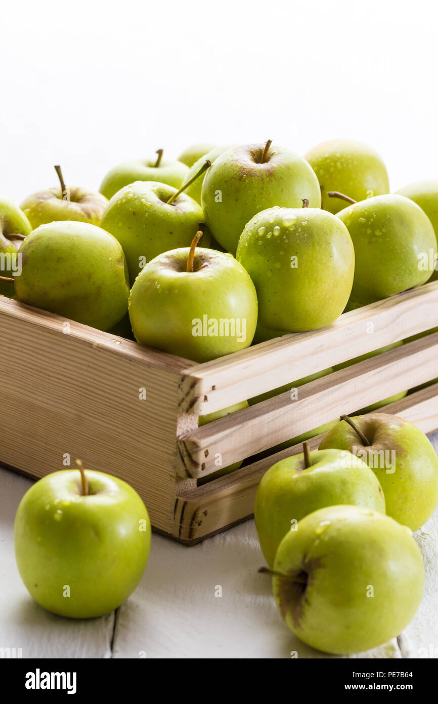 Grüne Äpfel in der Kiste schließen bis auf weißem Hintergrund mit selektiven Fokus auf Apfel mit Wassertropfen Stockfoto