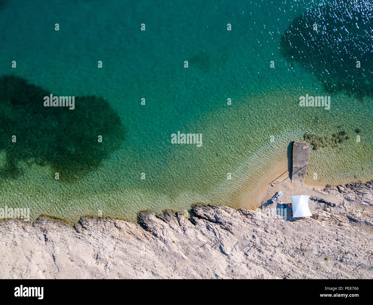 Luftaufnahme von einer trendigen Zelt, Brief aus der Sonne. Felsen am Meer und transparenten Meer Stock. Entspannen und Urlaub unter einem weißen Zelt von Felsen umgeben Stockfoto