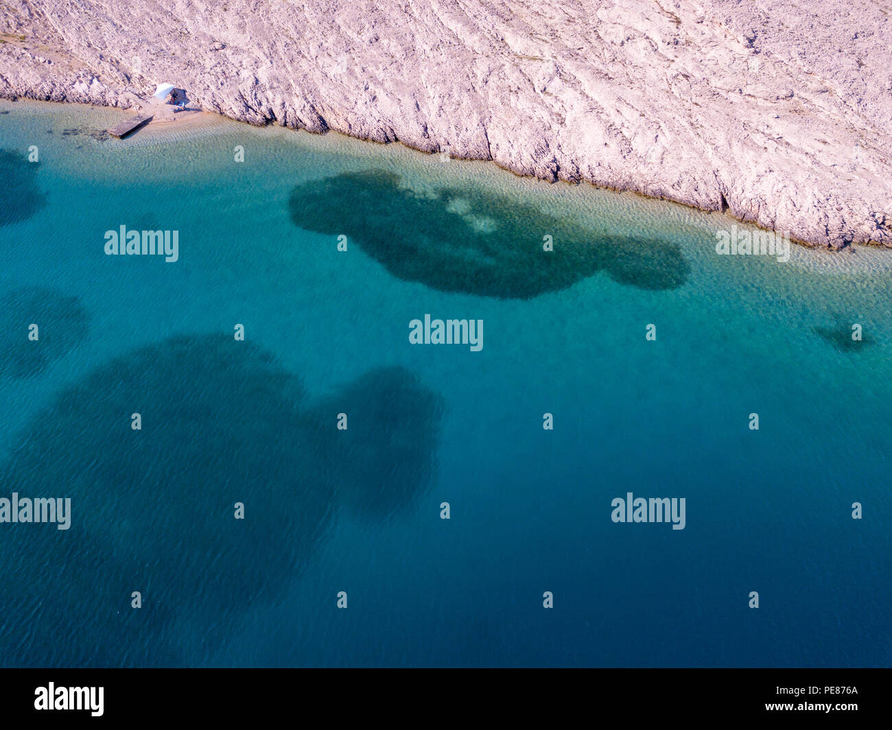 Luftaufnahme von einer trendigen Zelt, Brief aus der Sonne. Felsen am Meer und transparenten Meer Stock. Entspannen und Urlaub unter einem weißen Zelt von Felsen umgeben Stockfoto