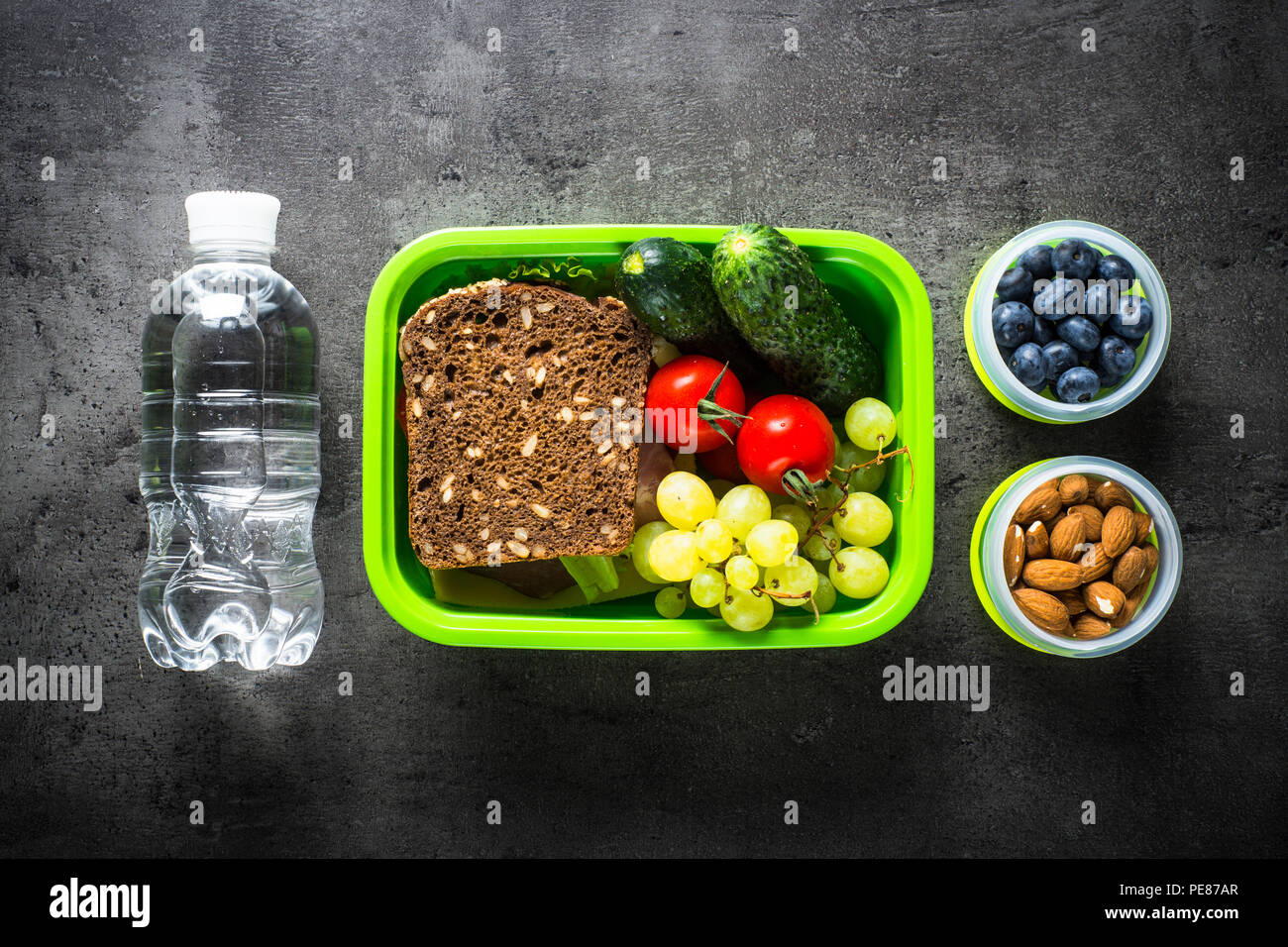 Lunch Box mit Sandwich, Gemüse, Bananen, Wasser, Nüsse und Beeren. Ansicht von oben mit der Kopie auf schwarzen Hintergrund. Stockfoto