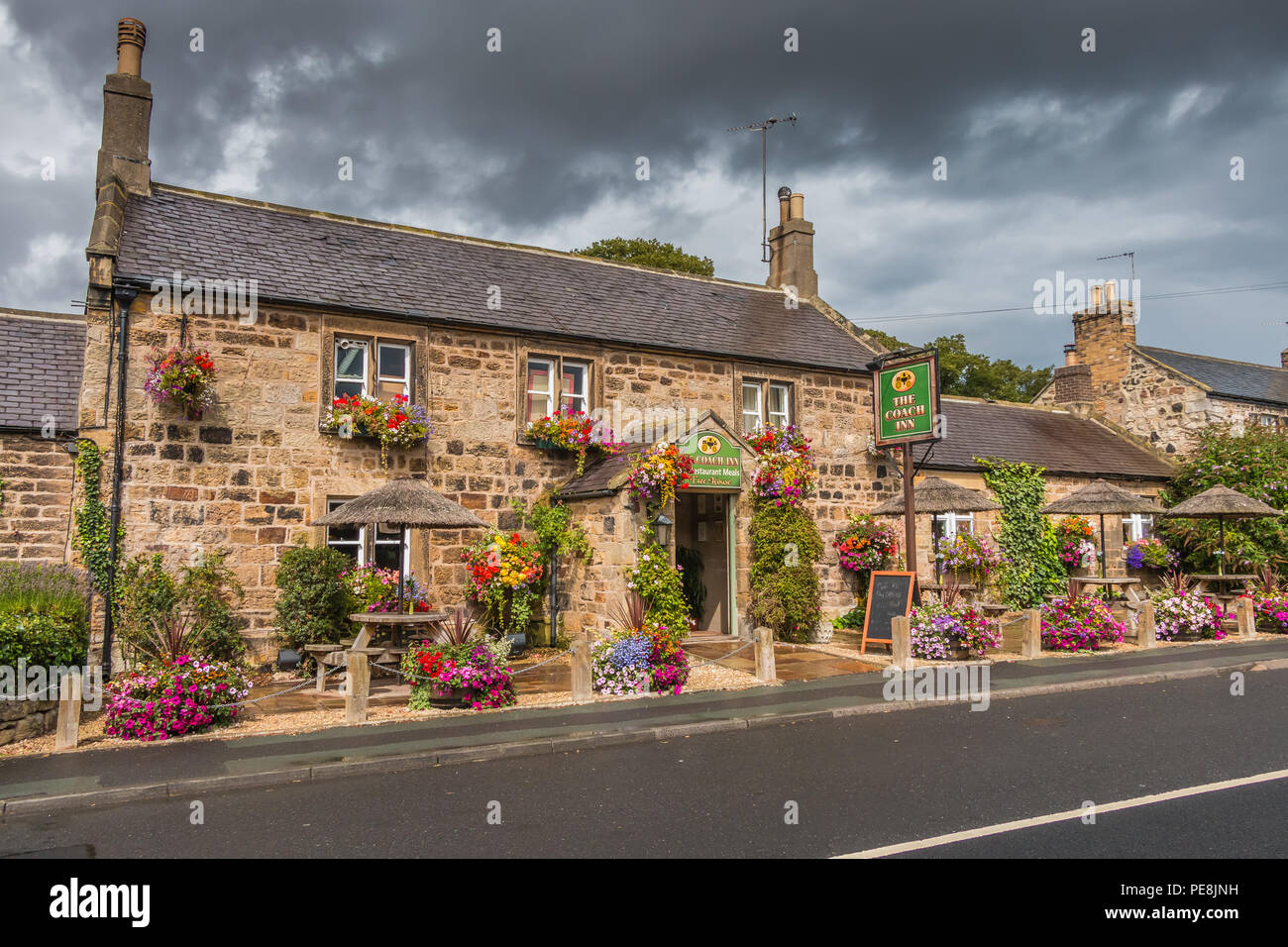 Traditioneller Englischer Pub, der Coach Inn, Lesbury, Northumberland mit einer farbigen Anzeige der Blüte hängende Körbe und Wannen Stockfoto