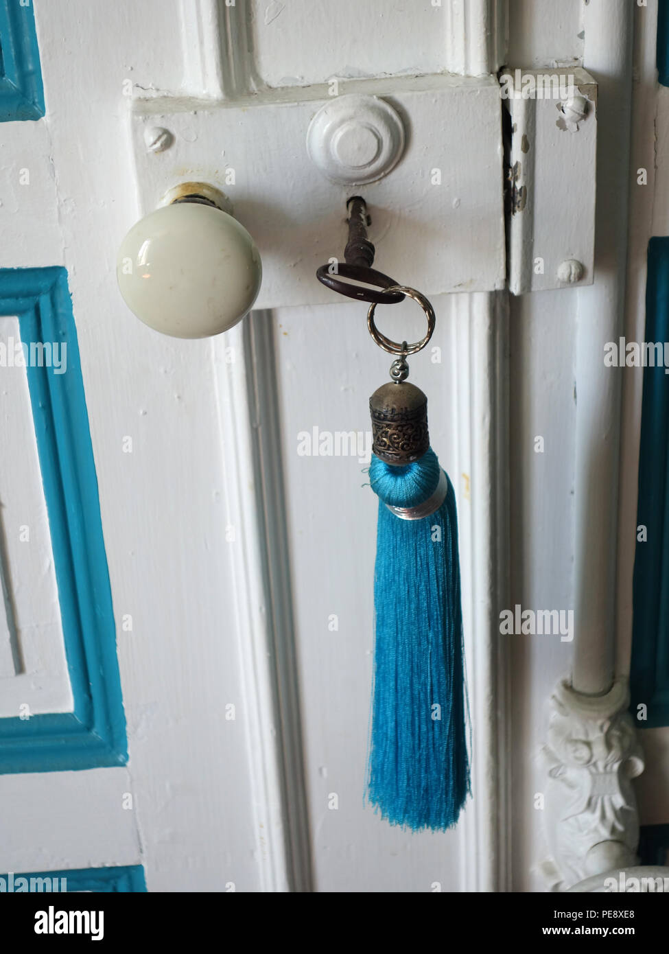 Türkis Blau tassle auf alten Schlüssel in das Türschloss in einem großen French House Stockfoto