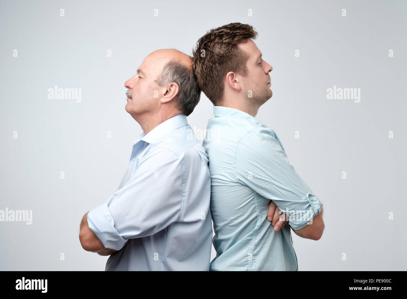 Seitliche Sicht auf zwei ernste Männer Vater und Sohn zurück, gegen einen weißen Hintergrund zu rücken. Streit oder Ärger Konzept Stockfoto