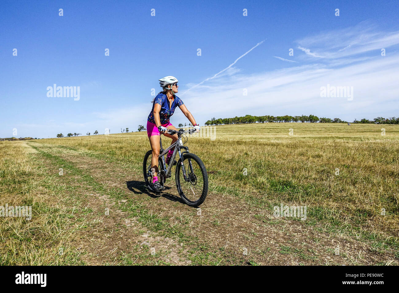 Frau Biker auf der Bergwiese, Fahrrad eine Fahrt, Krusne Hory Berge, Erzgebirge, Tschechische Republik Radfahren allein Stockfoto