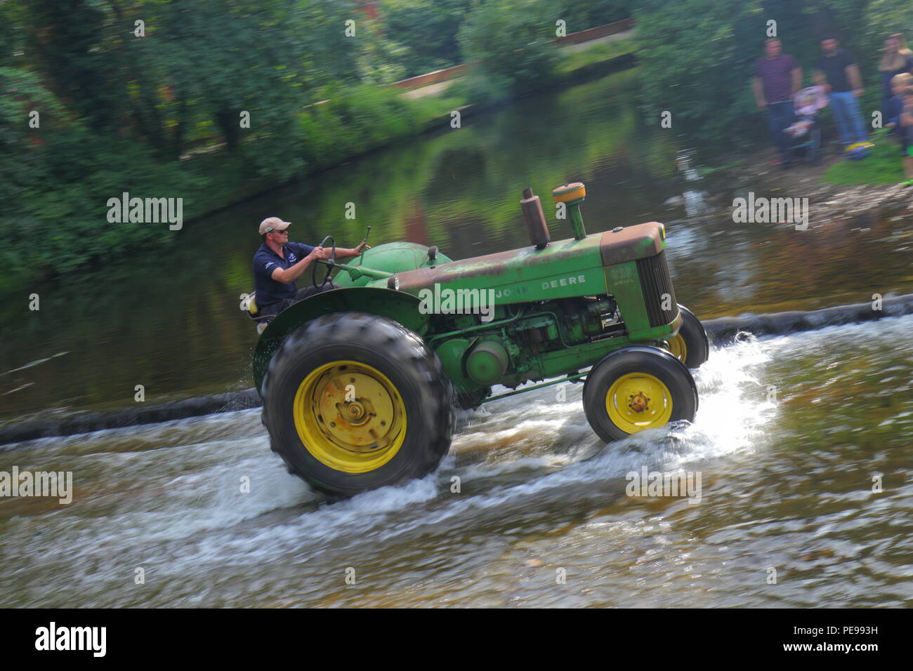 Ein John Deere Traktor überquert den Fluss Skell in Ripon während ein Konvoi von Traktoren, die von Newby Hall Traktor Festival Stockfoto