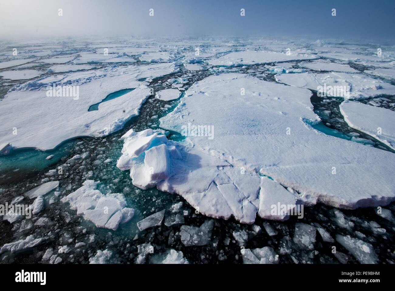 Brechen durch das Meereis, mit der Sonne hinter dem Nebel, tiefen Blau- und Grüntöne von Ocean obwohl das Eis Stockfoto