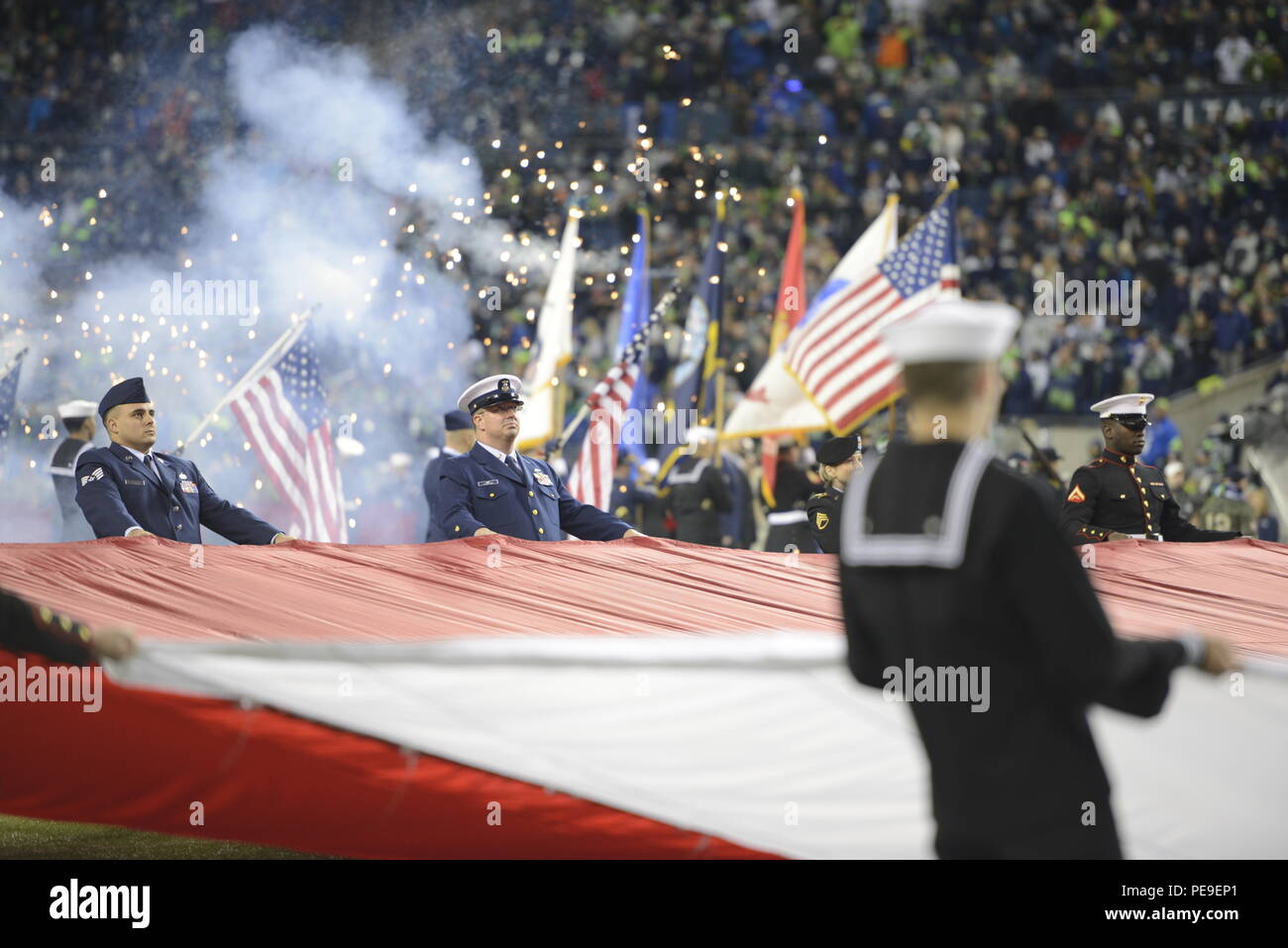 Master Chief Petty Officer Frank Donze (Mitte), ein Elektriker mit der Coast Guard Oberfläche Kräfte Logistik Zentrum in Seattle, hält eine riesige Flagge mit anderen service Mitglieder während der halftime show für begrüssen die Seahawks" Spiel bei CenturyLink Feld in Seattle, November 15, 2015. Während der Halbzeit, Das Team erkannte lokale Veterane und Vertreter aus den Puget Sound Ehre Flug während ihrer Präsentation auf dem Feld. (U.S. Coast Guard Foto von Petty Officer 3. Klasse Amanda Norcross) Stockfoto