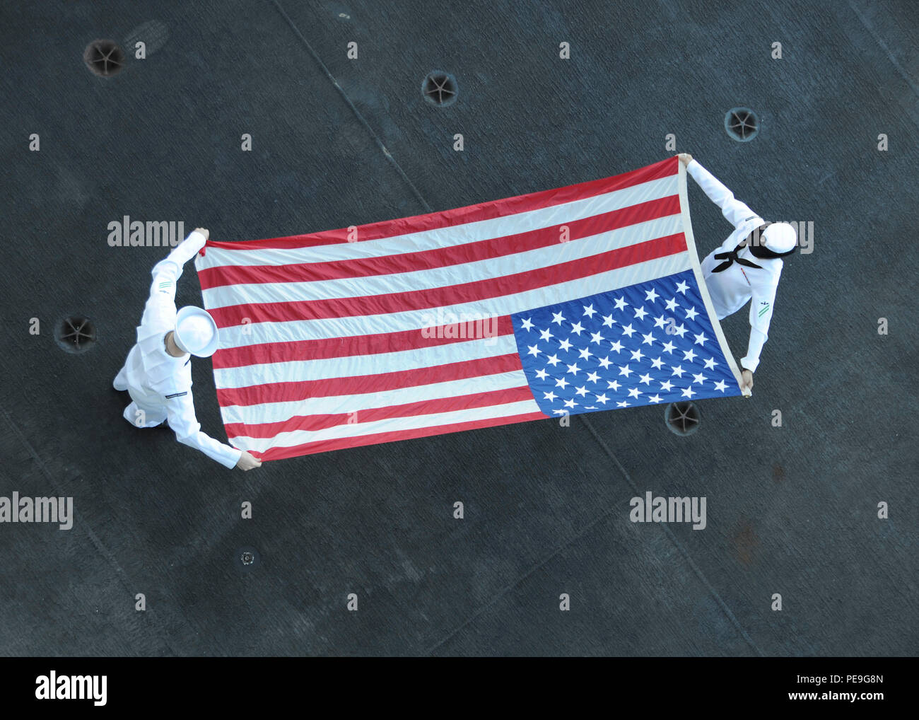 151117-N-NV 908-062 PAZIFISCHEN OZEAN (Nov. 17, 2015) Aviation Ordnanceman Airman Travis Bowman, Links, Lawrenceville, Ga. und Aviation Ordnanceman Airman Selena Gomez, aus Los Angeles, die amerikanische Flagge Falten nach der Abfahrt Joint Base Pearl Harbor-Hickam. Theodore Roosevelt in den USA 3 Flotte Einsatzgebiet als Teil eines weltweiten Einsatz auf dem Weg in den neuen Heimathafen in San Diego ein Drei-Carrier homeport shift zu vervollständigen. (U.S. Marine Foto von Mass Communication Specialist Seaman Chad M. Trudeau/Freigegeben) Stockfoto