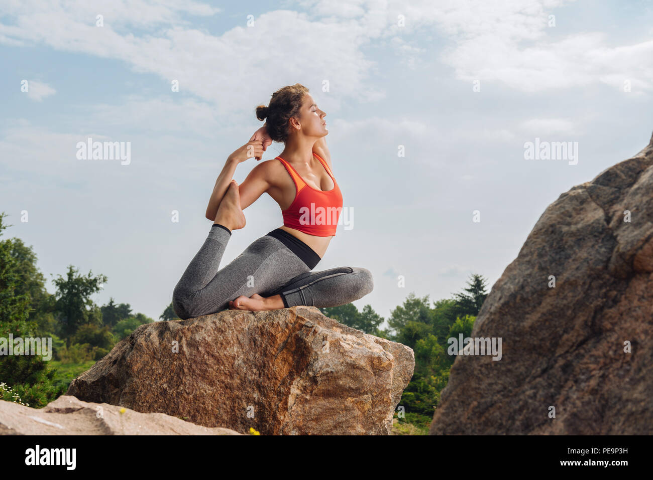 Fit und schlank Frau, Yoga Asana sitzt auf Felsen Stockfoto