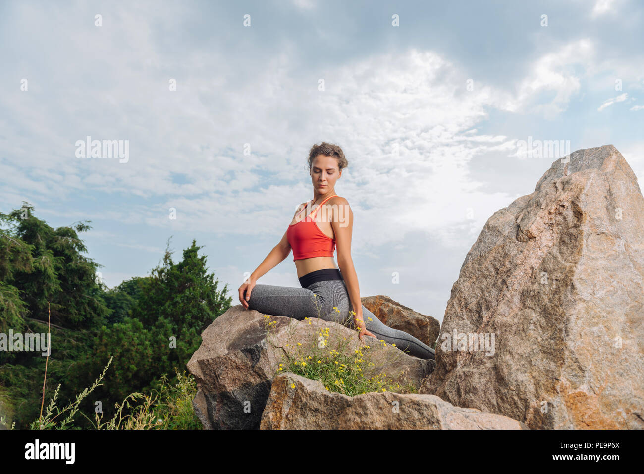 Curly schlanke Frau sitzt auf Felsen, während er nach dem Training Stockfoto