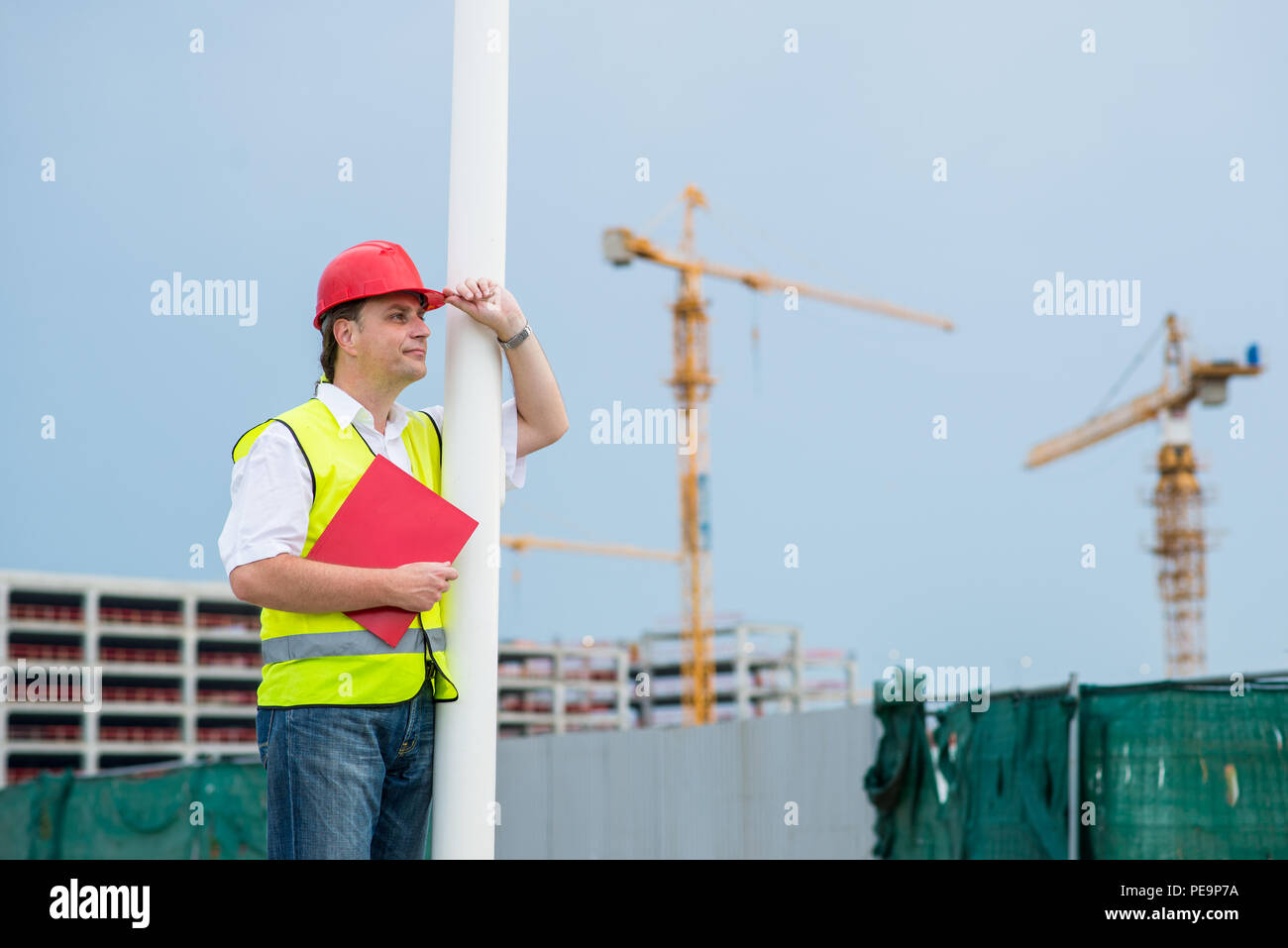 Ingenieur Kontrolle der Arbeit auf einer Baustelle mit Gebäuden und Krane im Hintergrund Stockfoto