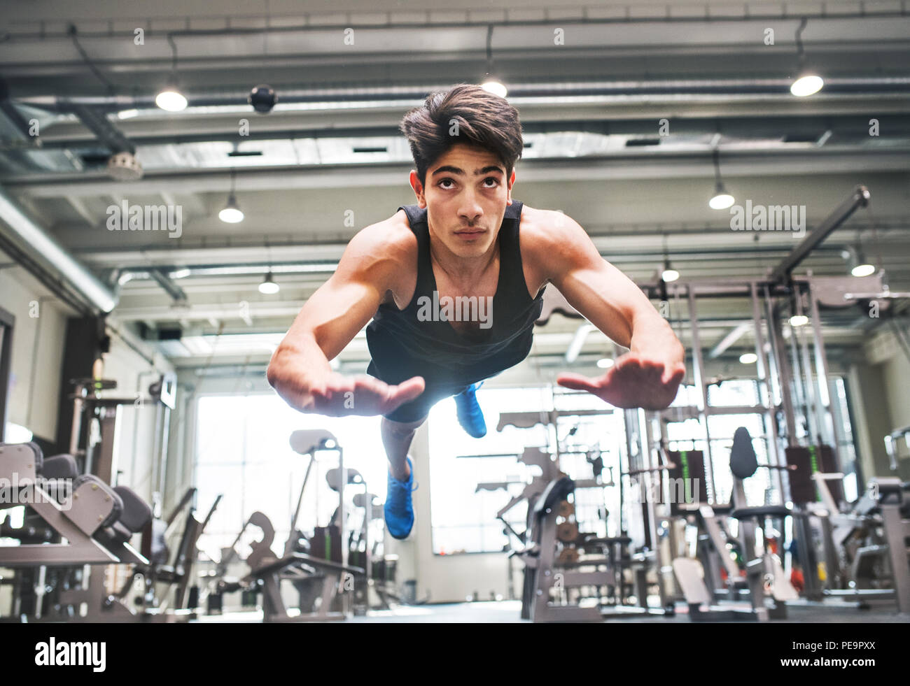 Hispanic junge passen Mann tun, Krafttraining, tut springen Push-ups im modernen Fitnessraum. Stockfoto