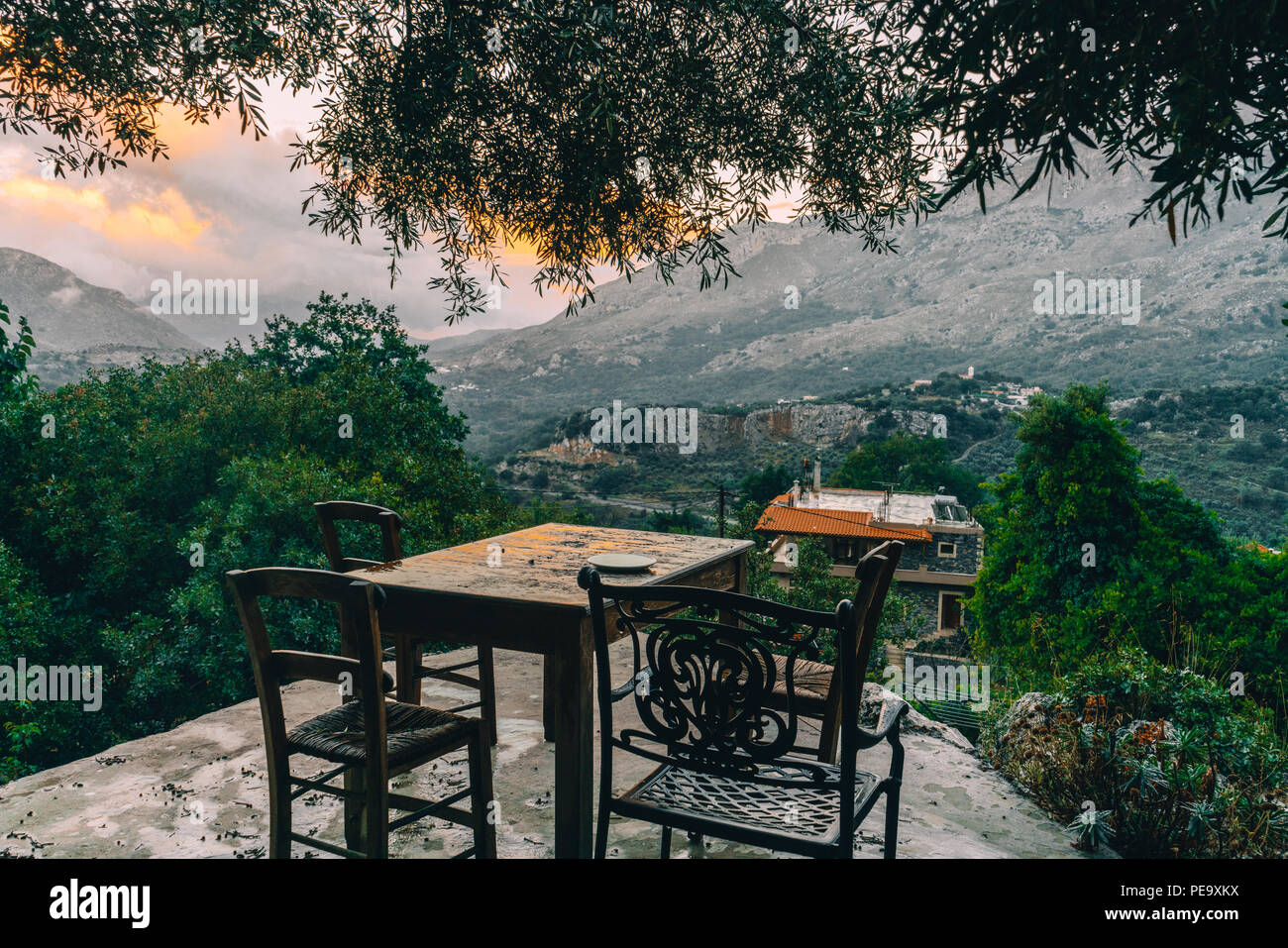 Leere Esstisch Mit Stuhlen Mit Blick Auf Die Berge Mit Niedrig Hangenden Wolken Und Grunen Olivenbaumen Suden Kretas Ordentlich Rethymno Griechenland Foto Genommen Stockfotografie Alamy
