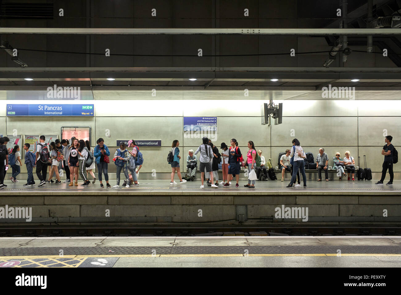 Chinesischer student Besucher warten auf einen Zug am Bahnhof St Pancras, London Stockfoto