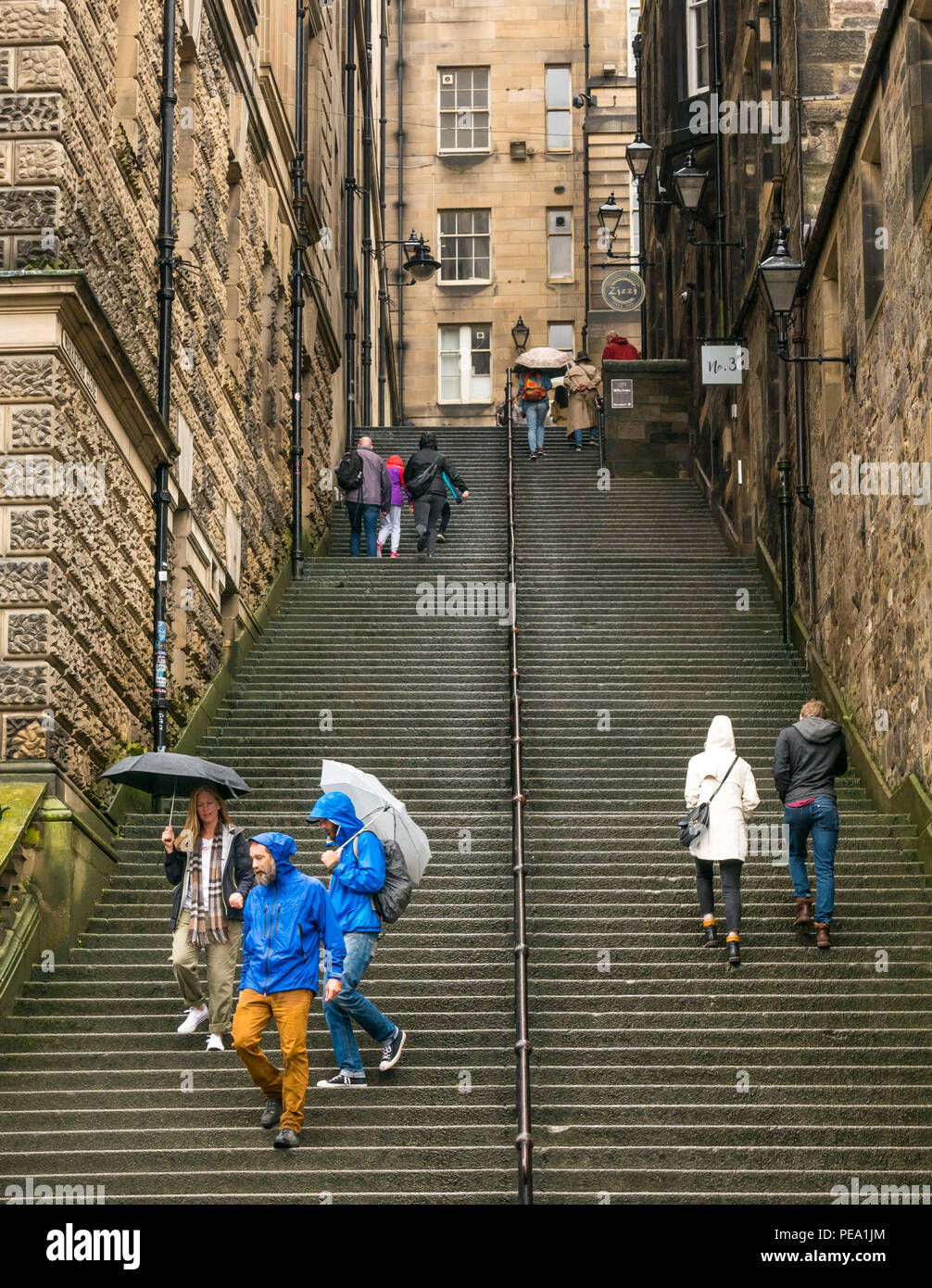 Touristen mit Sonnenschirmen im Regen zu Fuß bis lange steile Stufen in der Gasse, in der Nähe Warriston, Cockburn Street zur Royal Mile, Edinburgh, Schottland, Großbritannien Stockfoto
