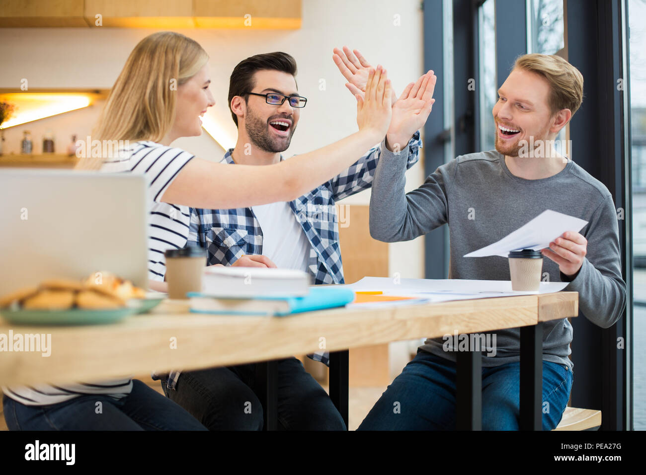 Tolle Arbeit. Positive nette intelligente Leute am Tisch sitzen und das Gefühl glücklich, während die anderen fünf Stockfoto