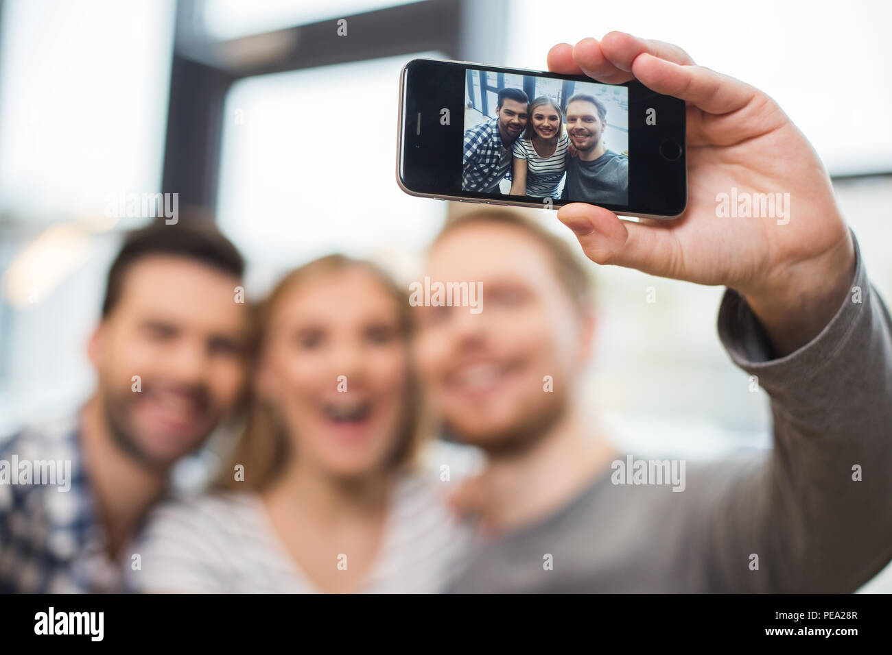 Guter Freund. Selektiver Fokus der ein Smartphone mit einem Foto der freudigen Happy Freunde auf dem Bildschirm Stockfoto