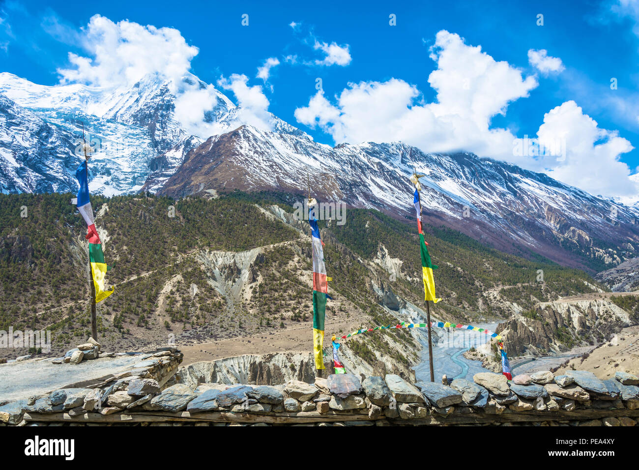 Bunte Fahnen über den Dächern der Häuser und gegen die verschneiten Berge im Himalaya, Nepal. Stockfoto