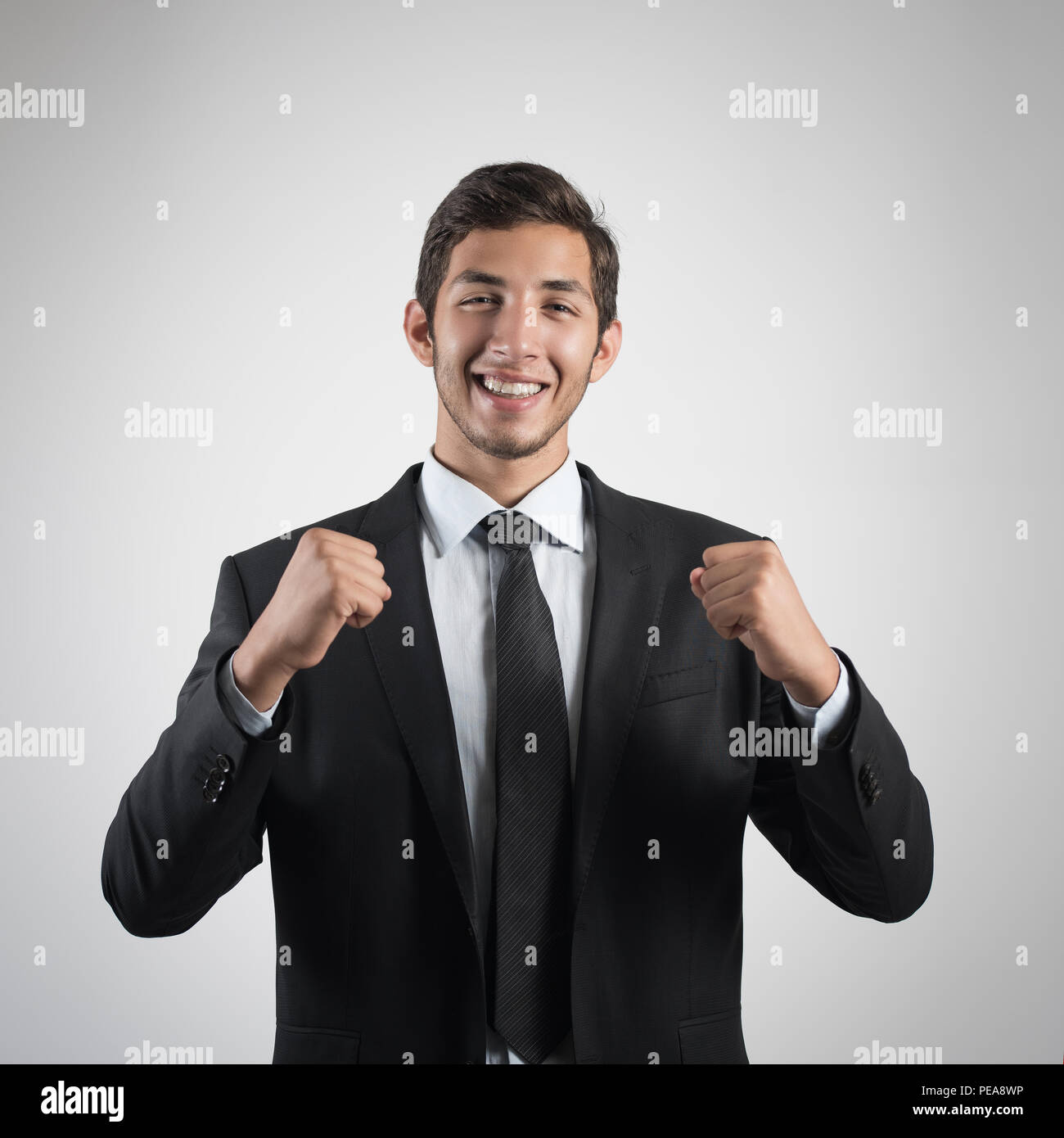 Junge gut aussehender Geschäftsmann in schwarzen Anzug lächelnd auf weißem Hintergrund. Portrait der junge Geschäftsmann Stockfoto