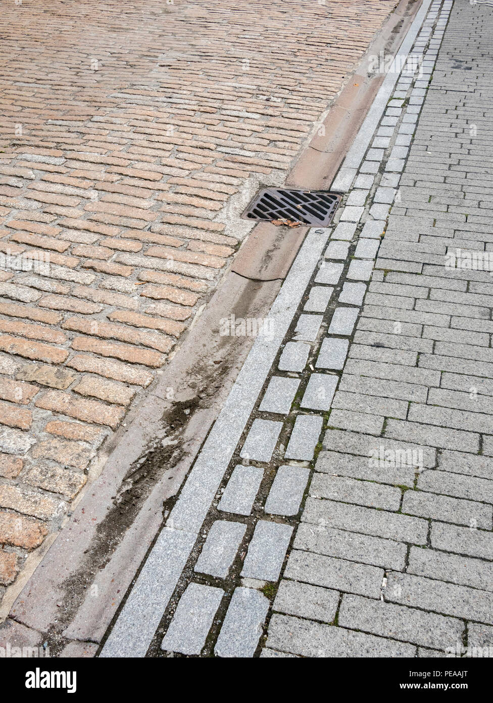 Cobblstoned Bereich mit Entwässerung Rinne und Abfluss - Metapher 'Down die Drain' Stockfoto