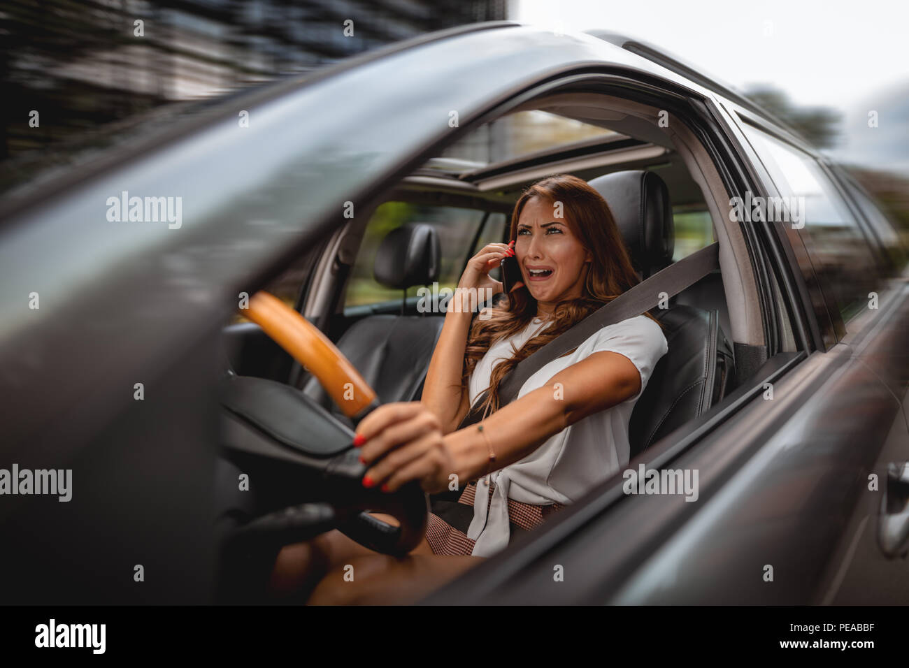 Frau mit Smartphone in ihrer Hand, die schlechten Nachrichten während der Fahrt ein Auto, und weinte. Stockfoto