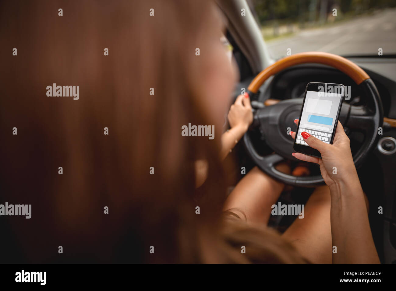 Frau SMS-Nachrichten auf dem Smartphone während des Lenkens eines Autos. Stockfoto