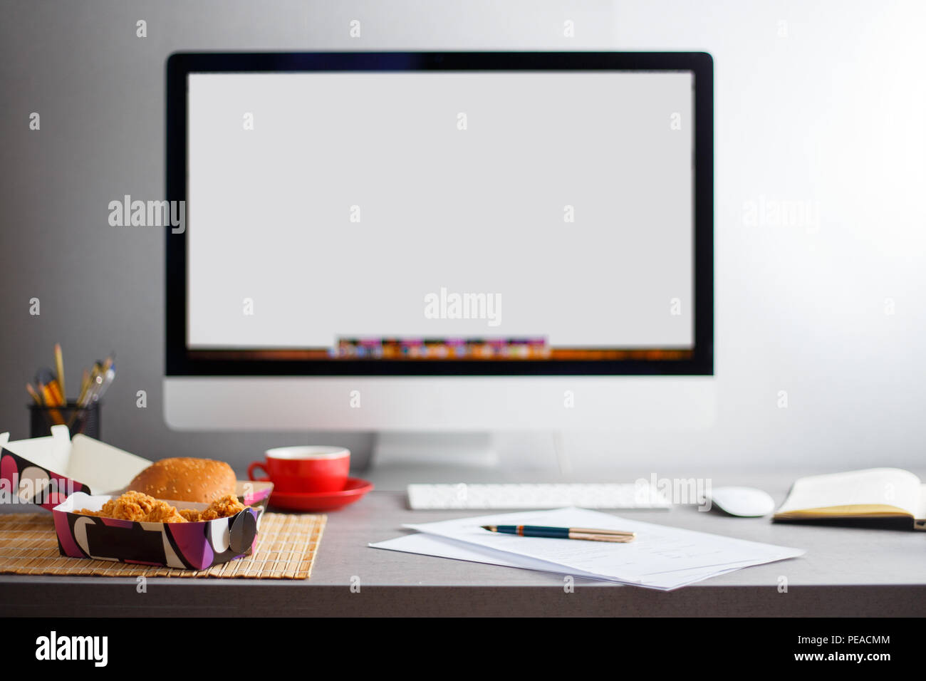 Mock-up-Bild der Arbeitsplatz mit leeren Monitor, Mittagessen und Papiere auf dem Schreibtisch Stockfoto