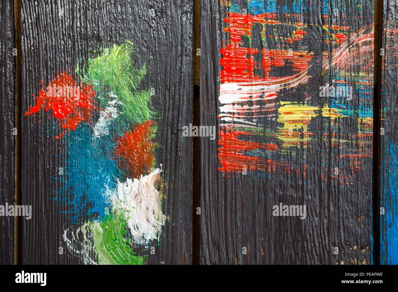 Auf einer hölzernen Hintergrund, die in schwarzer Farbe lackiert ist, Pinselstriche führte die Farbe von hellen Farben. Stockfoto