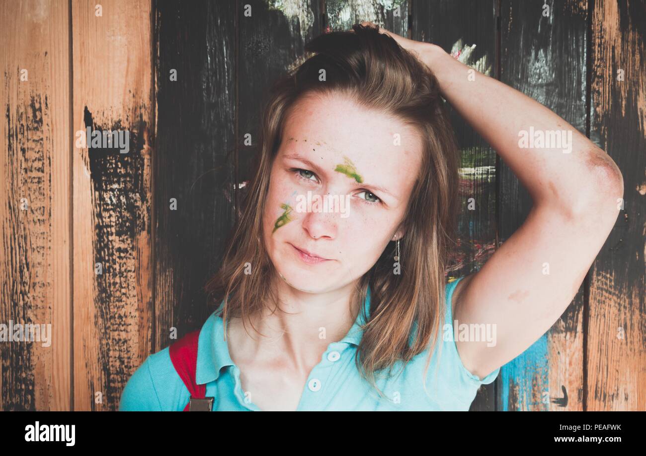 Schöne und junge Mädchen, die auf dem Hintergrund der bemalten Wand malen. Das Gesicht des Mädchens war mit einem grünen Farbspuren an - sie war Malen mit einem Br Stockfoto