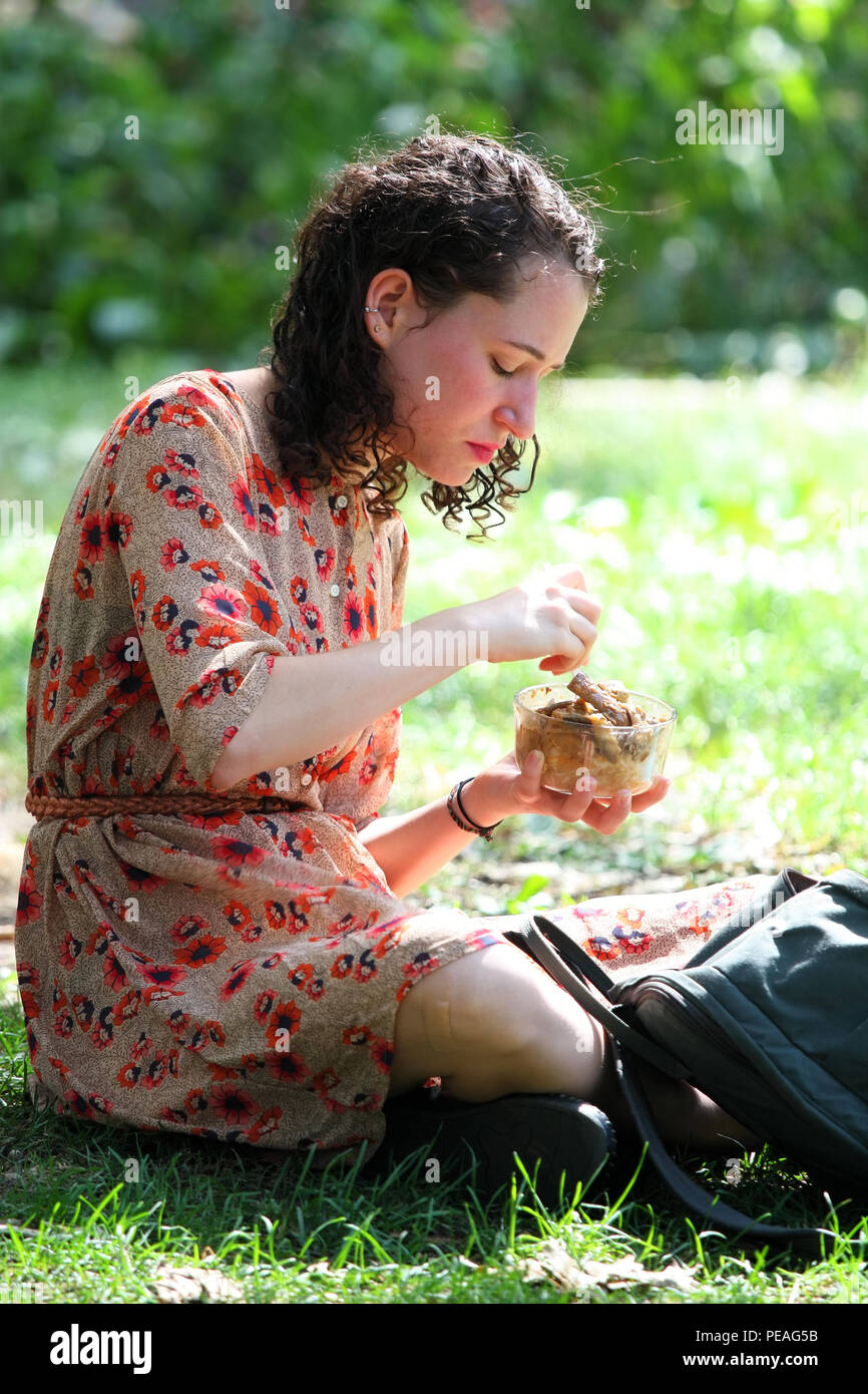 NEW YORK, NY - 05. SEPTEMBER: junge weiße Frau isst Mittag beim Sitzen auf Gras im Washington Square Park, Manhattan am 5. September 2016 in New York Stockfoto