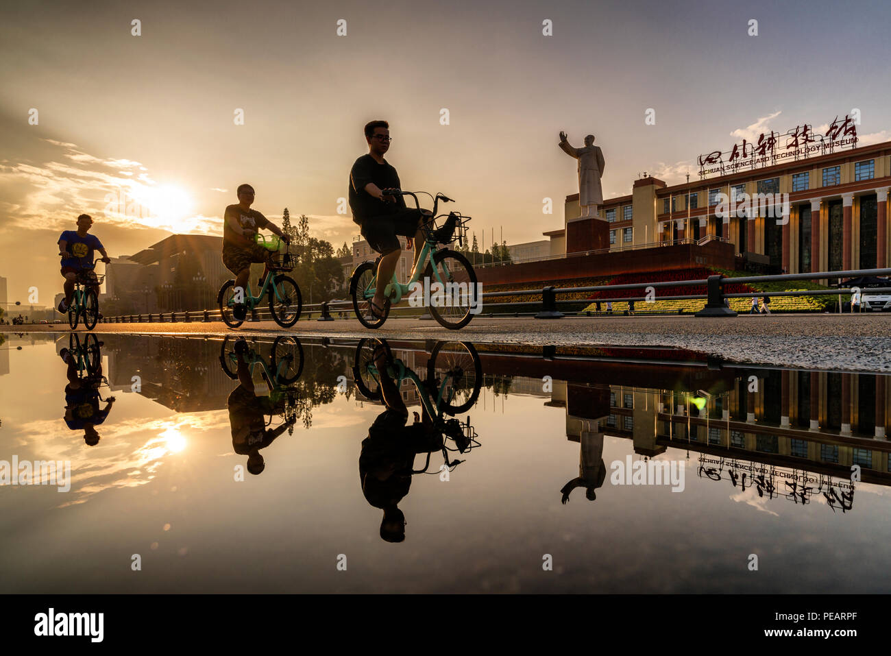 Chengdu, Sichuan, China, Menschen reiten Gemeinschafts-bikes über Mao Zedongs Statue vor Tianfu Square. Stockfoto