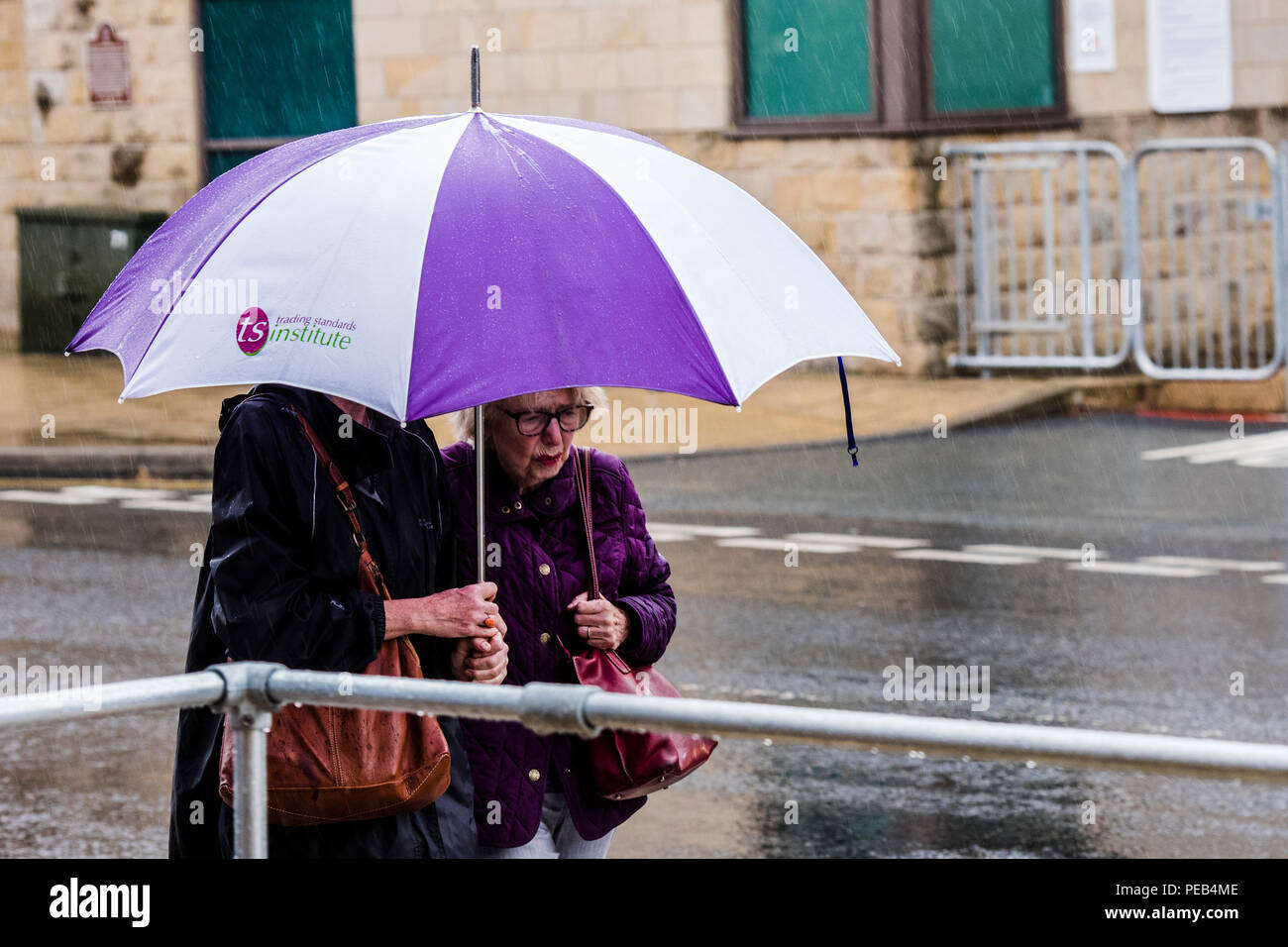 Zwei Frauen gehen in Regenguß, die gemeinsame Nutzung großer Regenschirm, Harrogate, North Yorkshire, Großbritannien Stockfoto