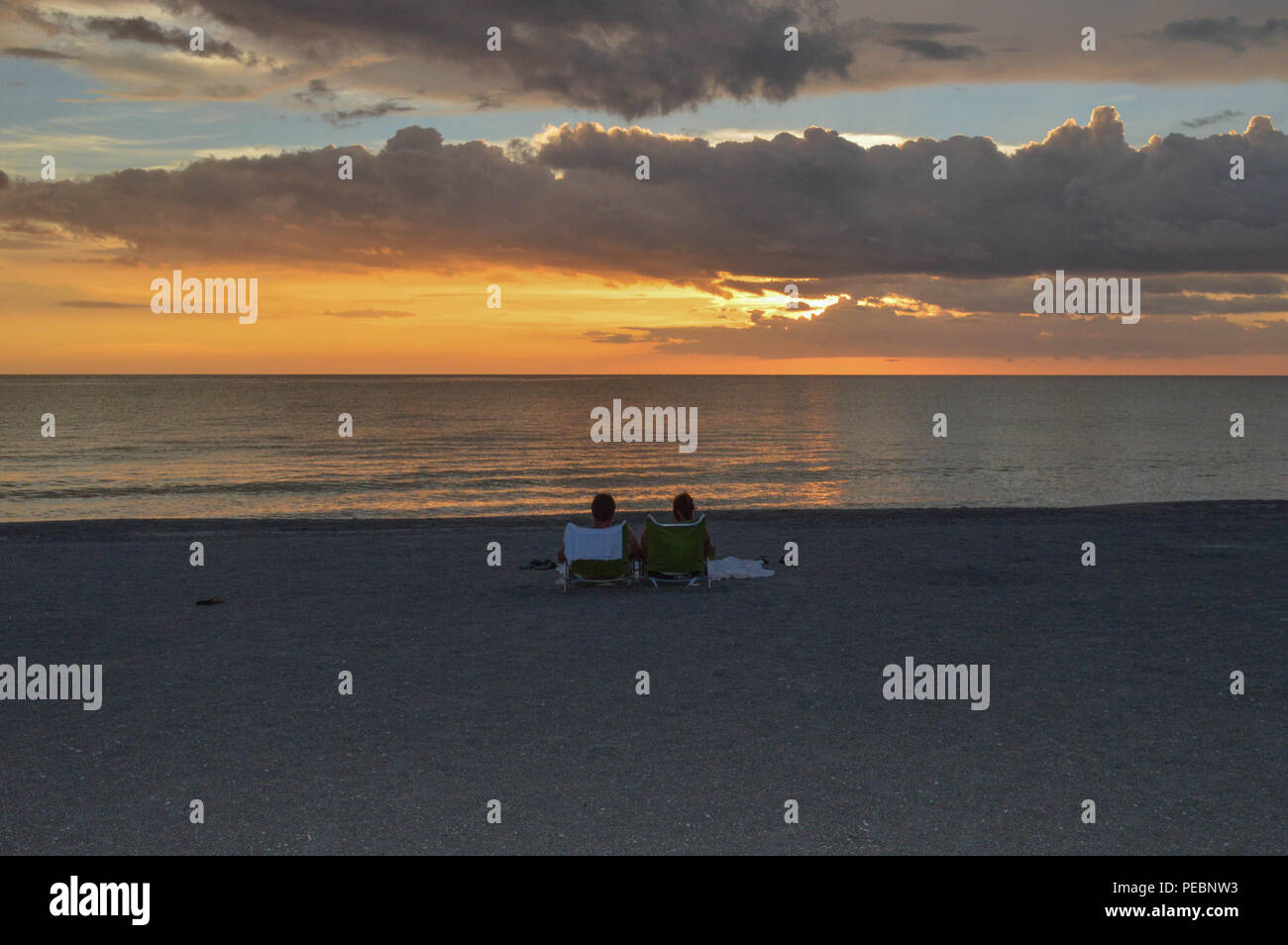 Paar entspannen Liegen Anzeigen schöner Sommerabend Lichtreflexionen Tropical Island Ocean Golf Sonnenuntergang ruhige Ferienhäuser Ufer Wasser Himmel Wolken Stockfoto