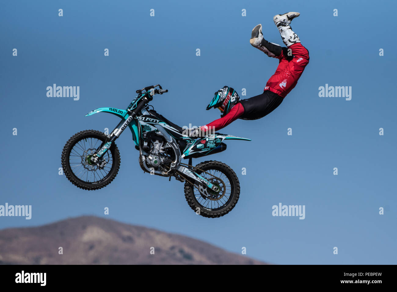 Stunt Rider in rot Kostüm hängt an den Sitz der Motorrad während über den Himmel fliegen auf springen während Flying U Rodeo im Ventura County Fair am 1. August Stockfoto
