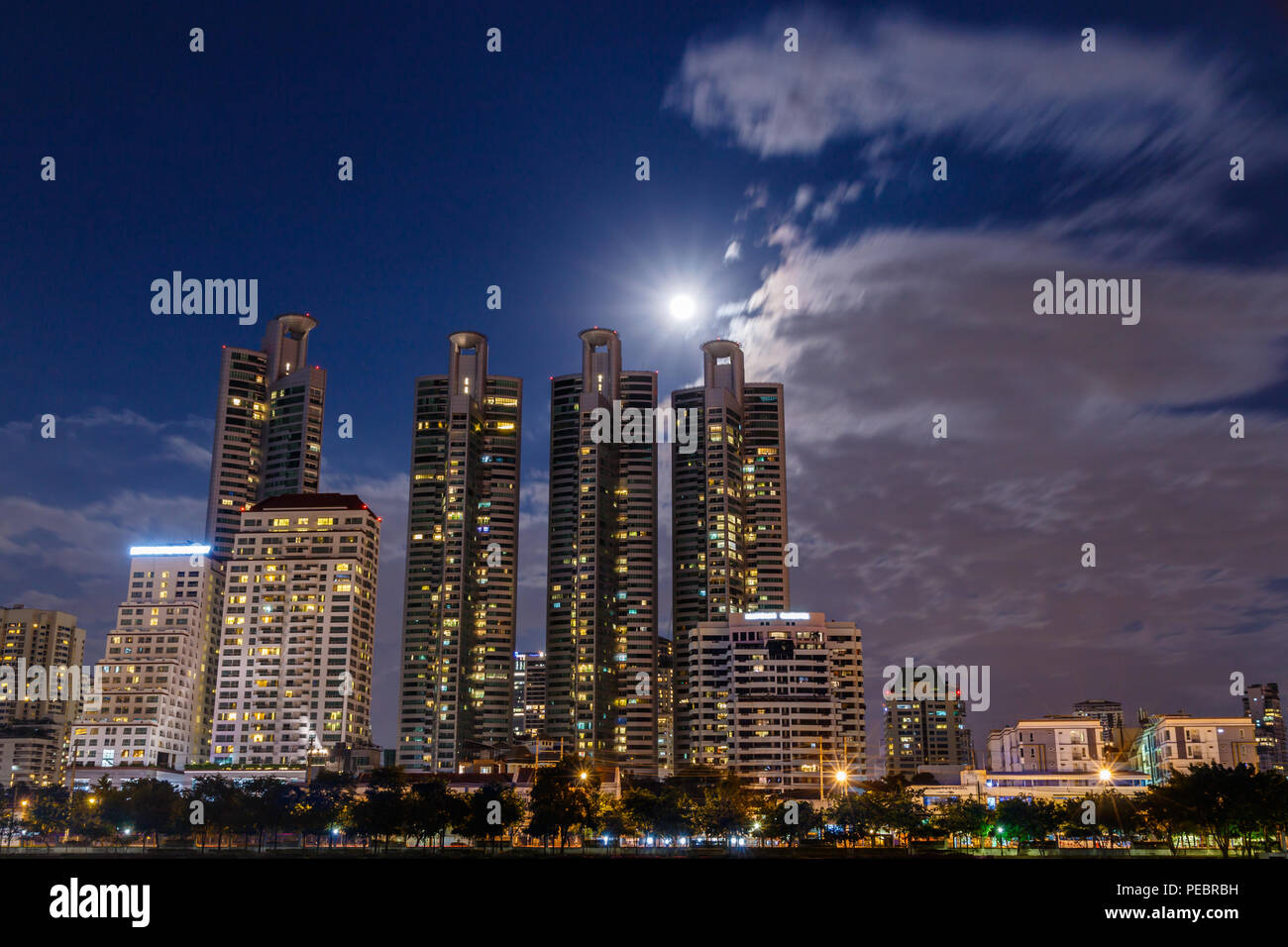 Bangkok nacht Stadtbild, mit Blick über den See im Queen Sirikit National Convention Centre. Vollmond und Wolken im Hintergrund. Stockfoto
