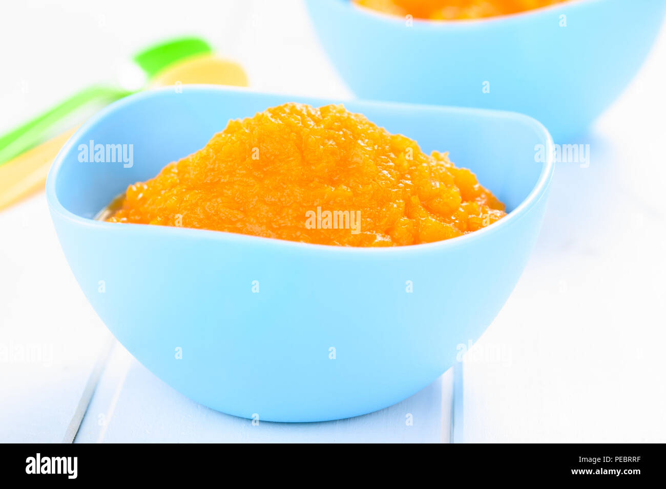 Frische hausgemachte vegan Kürbispüree oder Brei in blaue Schale, können als Baby oder Kleinkind essen, auf weißem Holz fotografiert (selektive Fokus) verwendet werden. Stockfoto