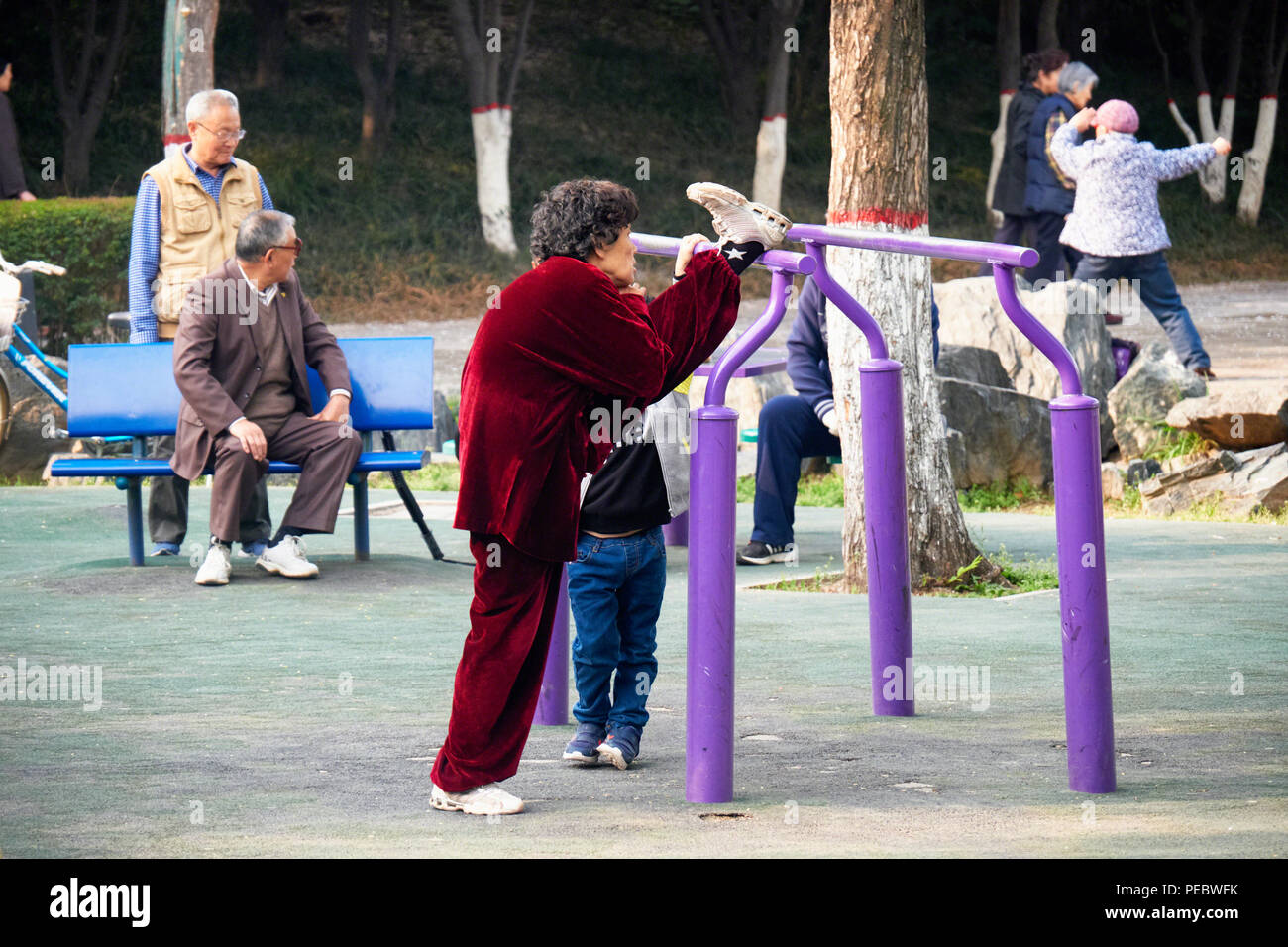 Eine ältere chinesische Frau ihr Bein strecken auf einem Spielplatz, Xi'an, China Stockfoto