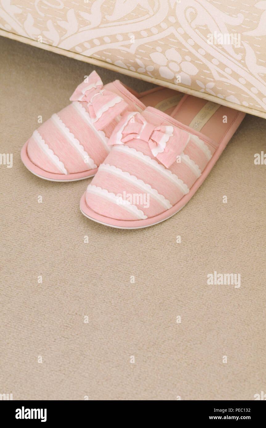 Rosa Damen Hausschuhe unter einer Schlafcouch Stockfoto