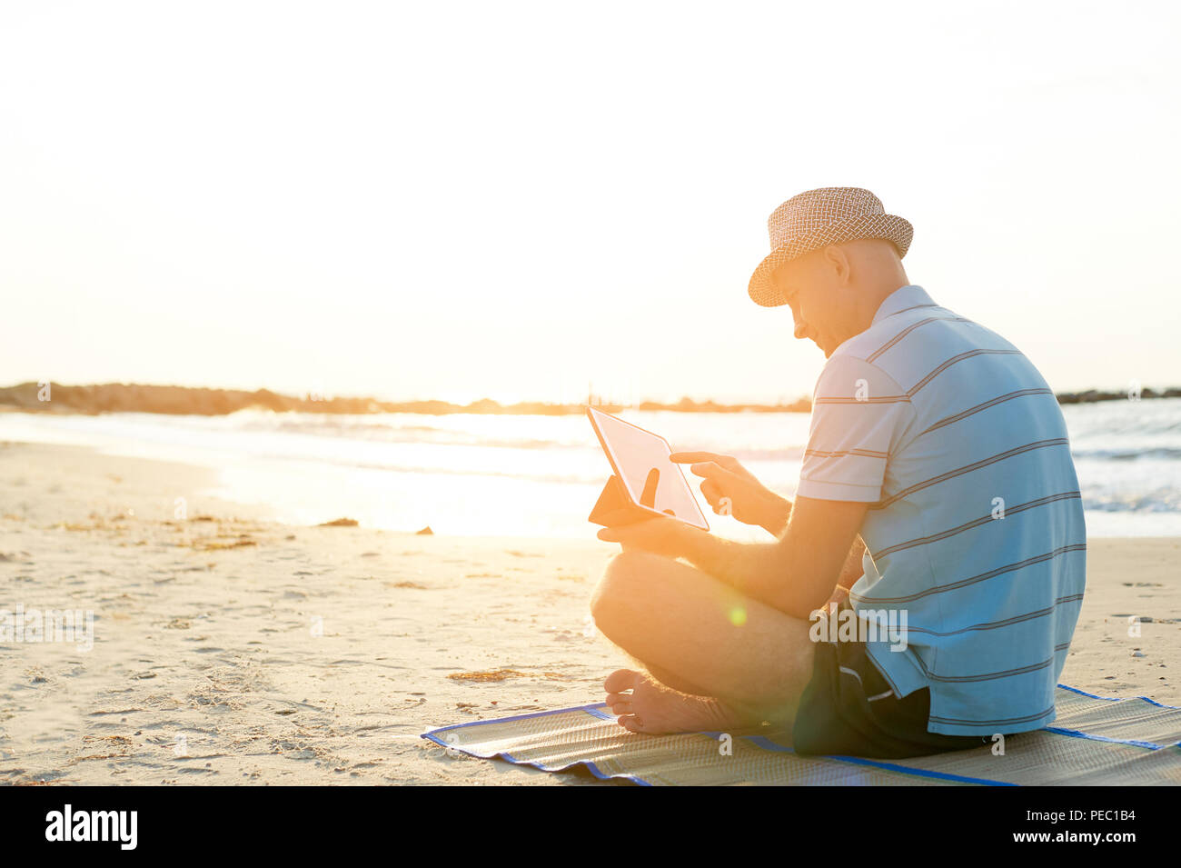 Älterer Mann bei der Arbeit auf seinem Laptop am Strand bei Sonnenuntergang, Freiberufler Konzept in Reisen Stockfoto Älterer Mann bei der Arbeit auf seinem Laptop am Strand bei Sonnenuntergang, Freiberufler Konzept in Reisen Stockfoto