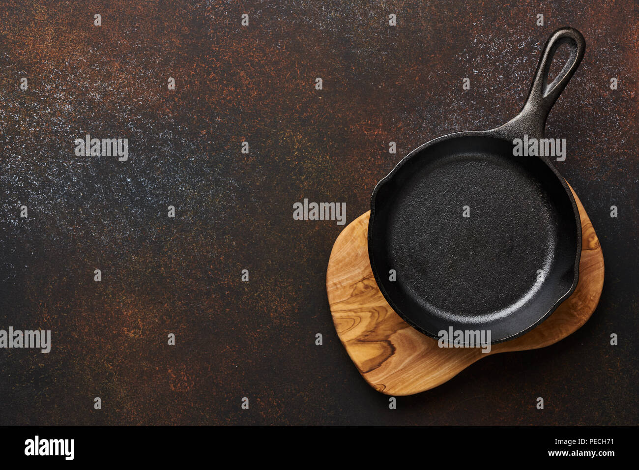 Leeren schwarzen Bratpfanne auf oliv Holzbrett über Braun konkreten Hintergrund mit kopieren. Stockfoto