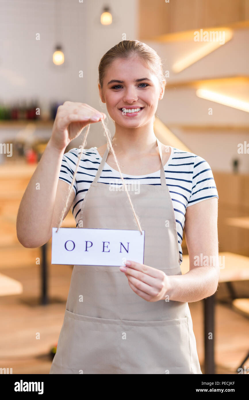 Bereit für die Besucher. Freudige angenehm positive lächelnde Frau und an Sie, während Ihr Cafe öffnen Stockfoto